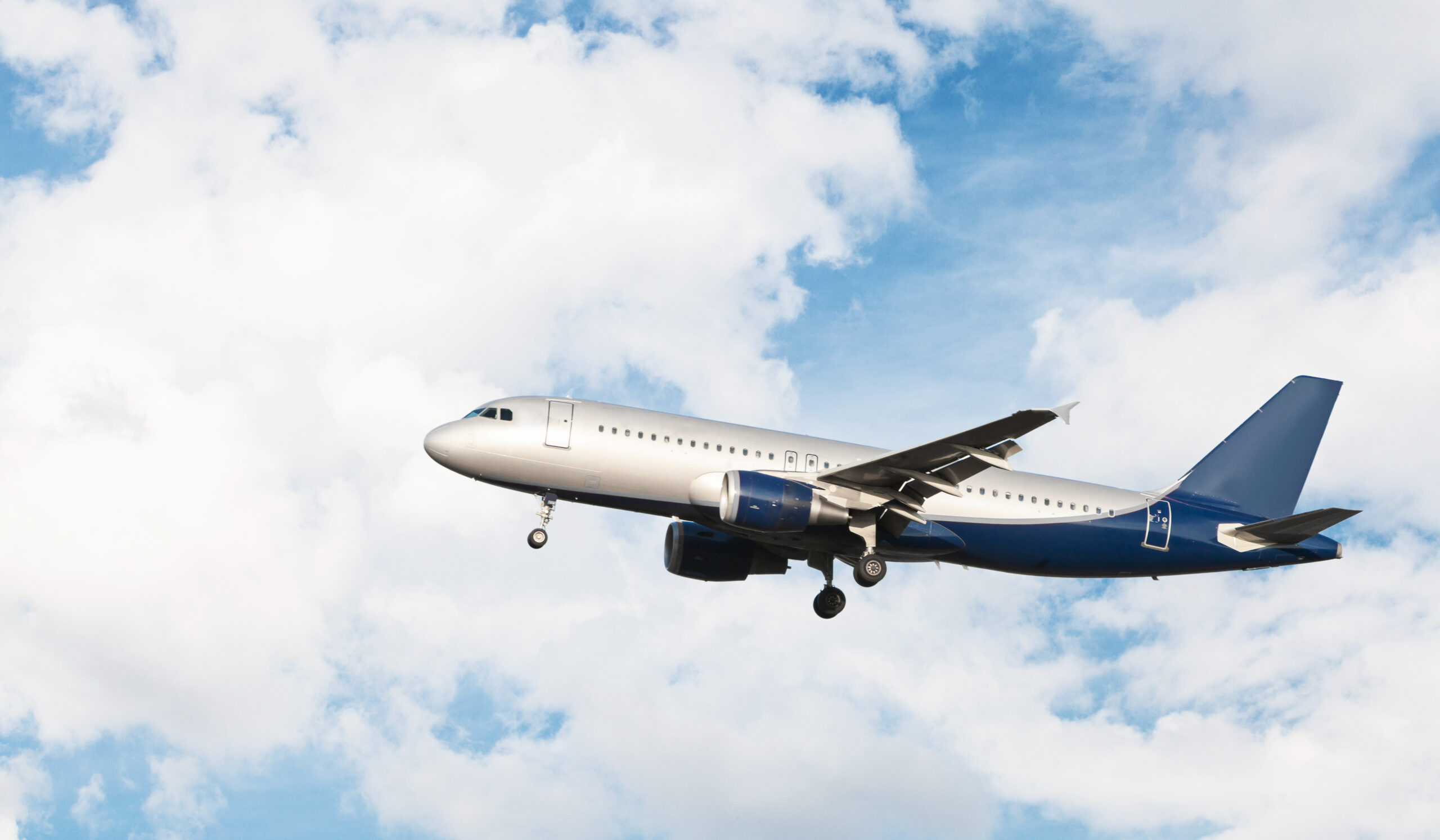 airplane flying in cloudy sky scaled